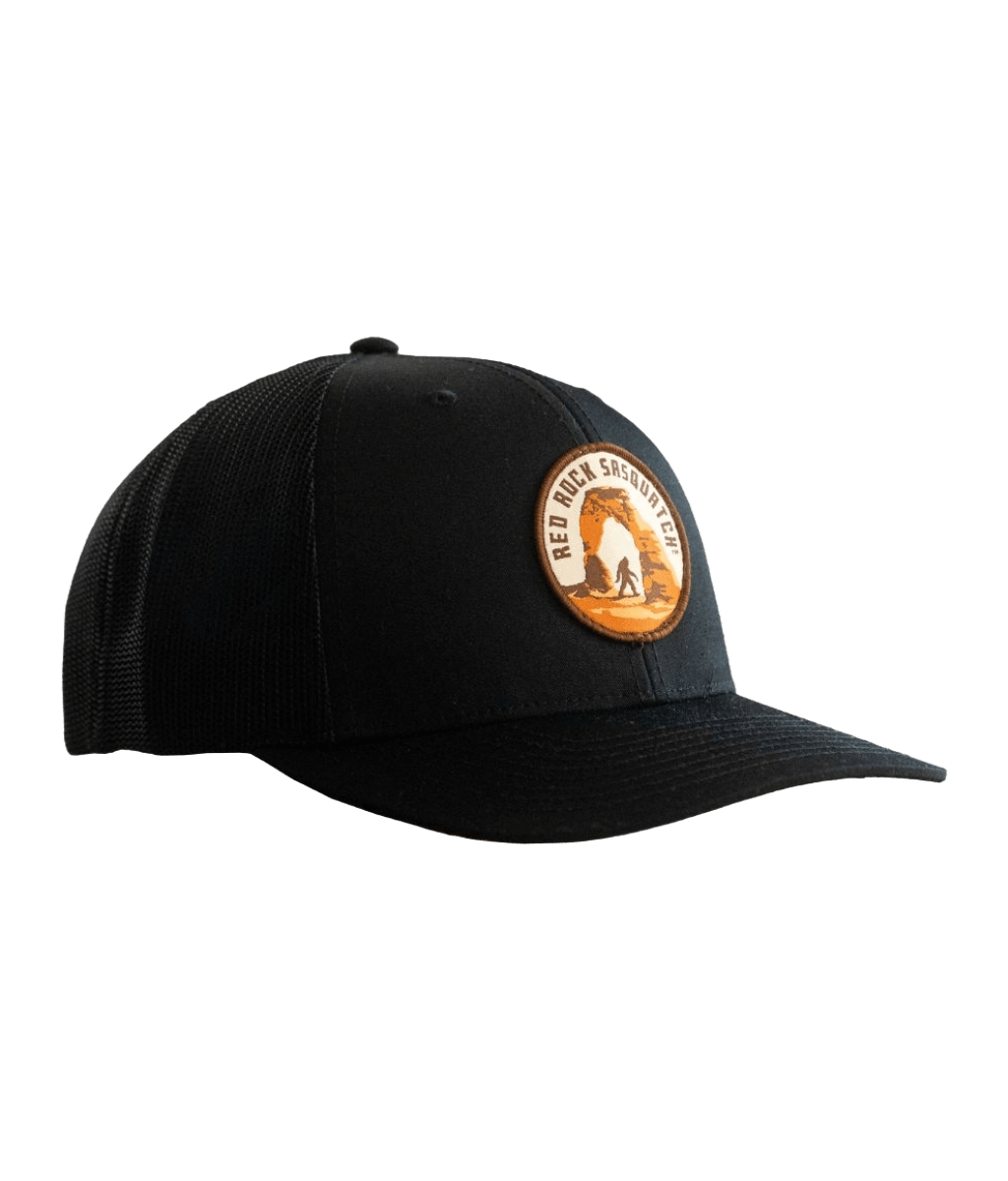 Black trucker hat with a patch featuring Delicate Arch and a Sasquatch figure.