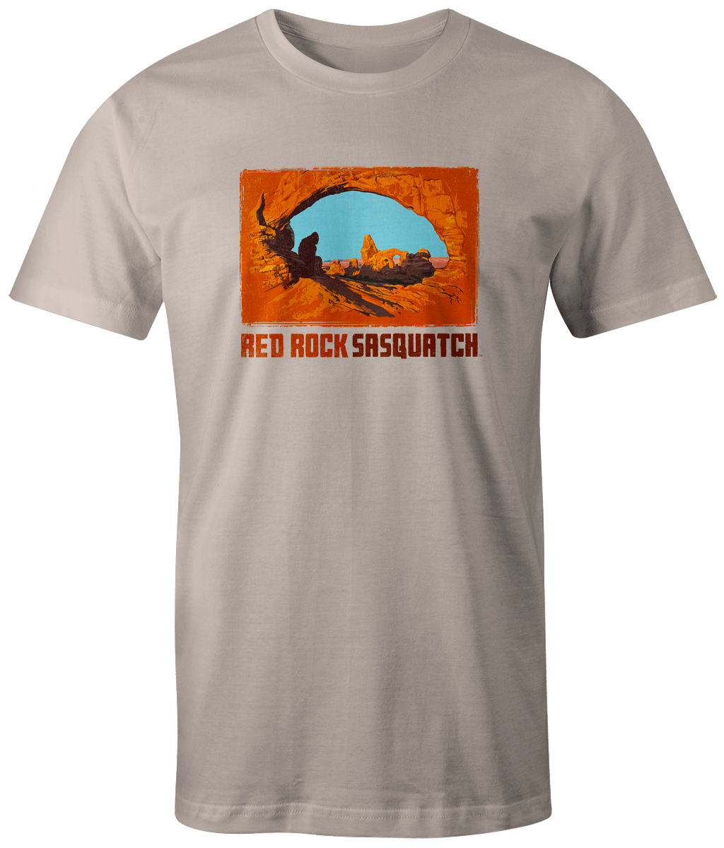 Ivory short-sleeve t-shirt displaying a unique graphic of Sasquatch at Delicate Arch.