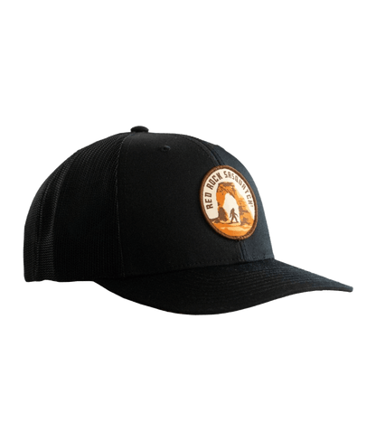 Black trucker hat with a patch featuring Delicate Arch and a Sasquatch figure.