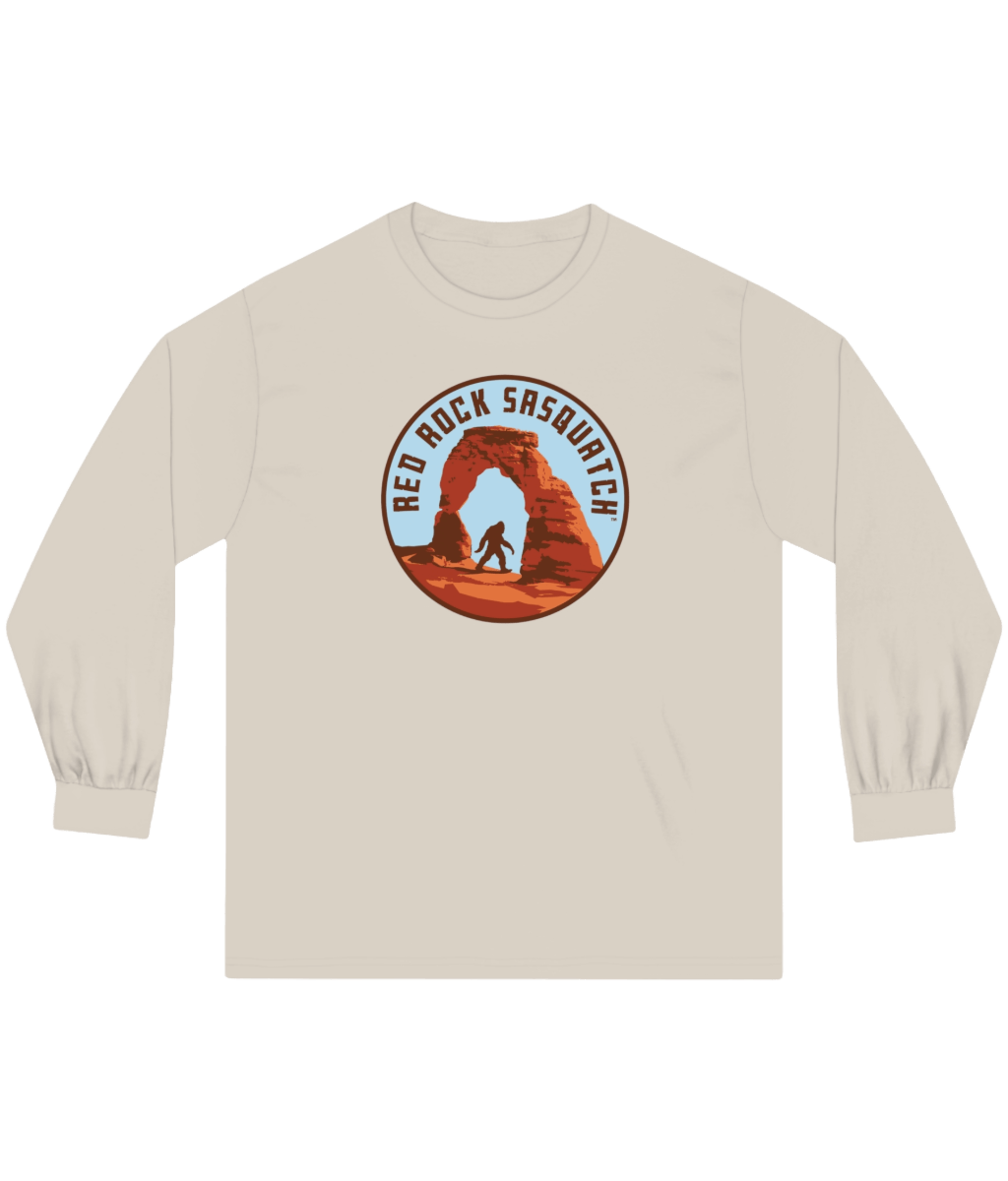 Sand-colored long-sleeve Delicate Arch tee. Displays a unique graphic of Sasquatch at Delicate Arch.